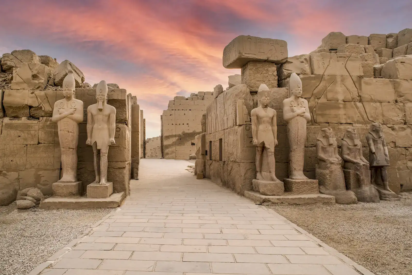 Statues at Karnak temple in Luxor under a sunset sky